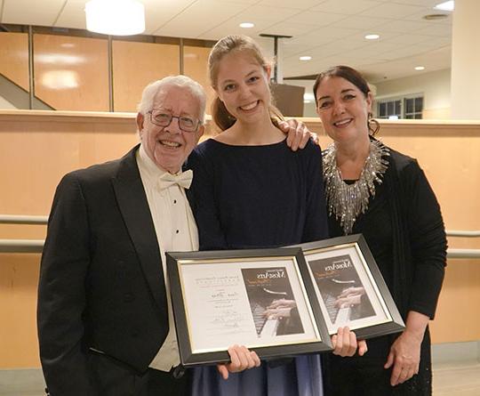 young girl with award certificates with woman and older man