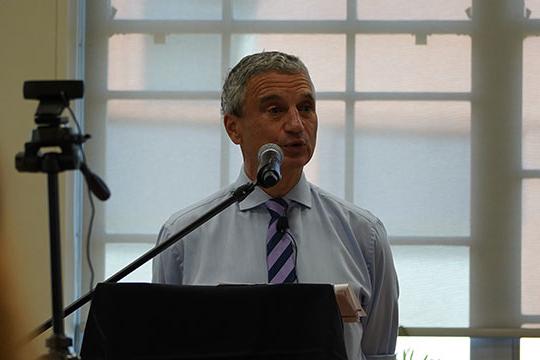 man with shirt and tie speaking at podium